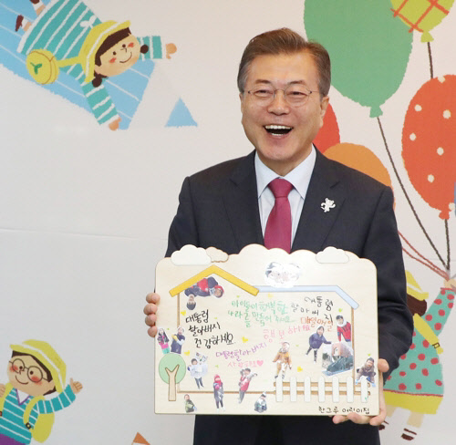문재인 대통령이 24일 서울 도봉구 한그루 어린이집을 방문해 어린이들과 마술공연 관람을 마친 뒤 선물을 받고  활짝 웃고 있다. 이날은 문 대통령의 66번째 생일로, 어린이들이 그림과 손글씨로 된 선물을 준비했다. 연합뉴스